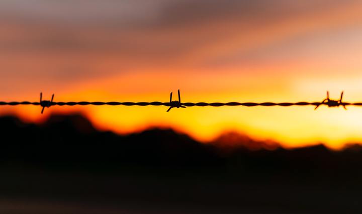 Sunset behind a string of barb wire,